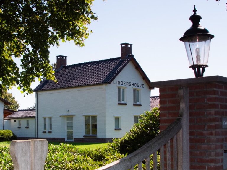 Het witte woonhuis van De Lindershoeve met houten toegangshek in Bergeijk